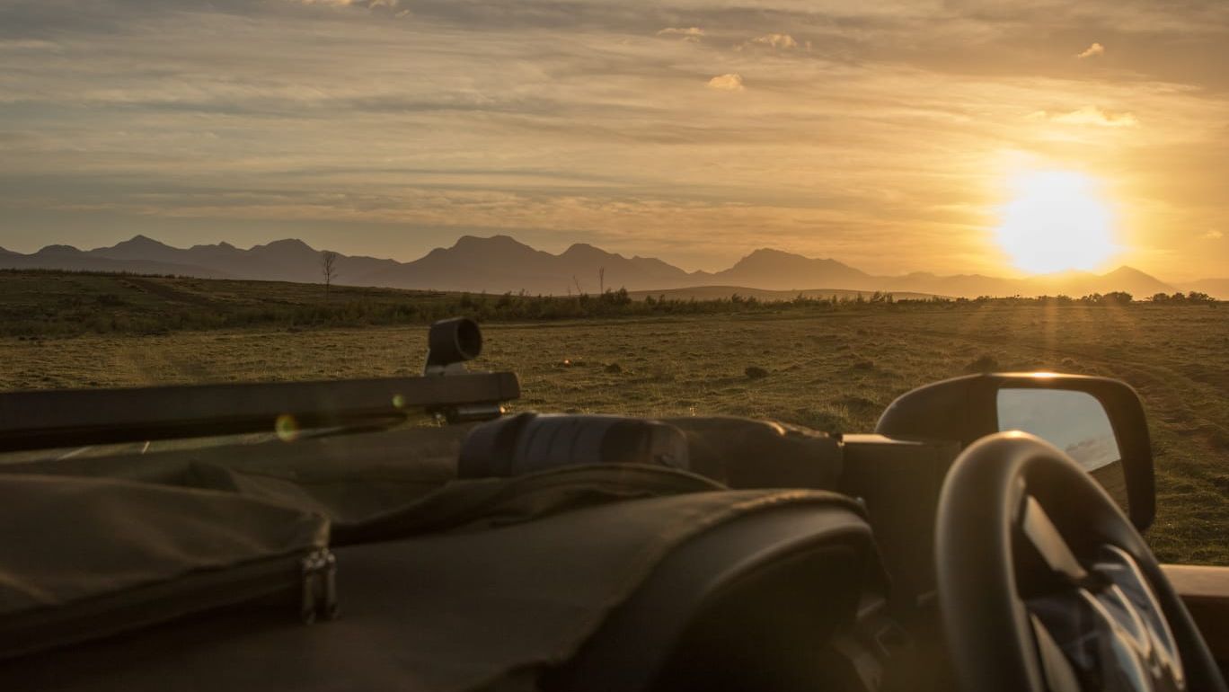 Pirschfahrt in Afrika: Blick aus einem Game Drive-Fahrzeug auf die Savanne Afrikas bei Sonnenuntergang