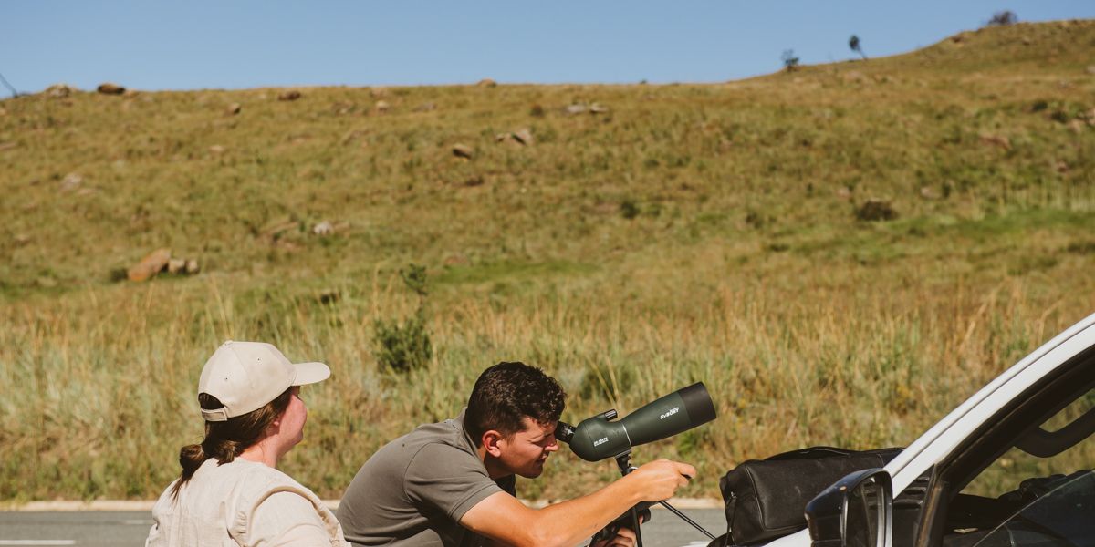 Two people look into the air through a telescope