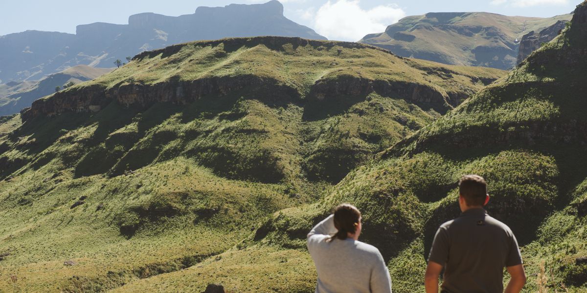 Two people look into the distance at the mountainous landscape