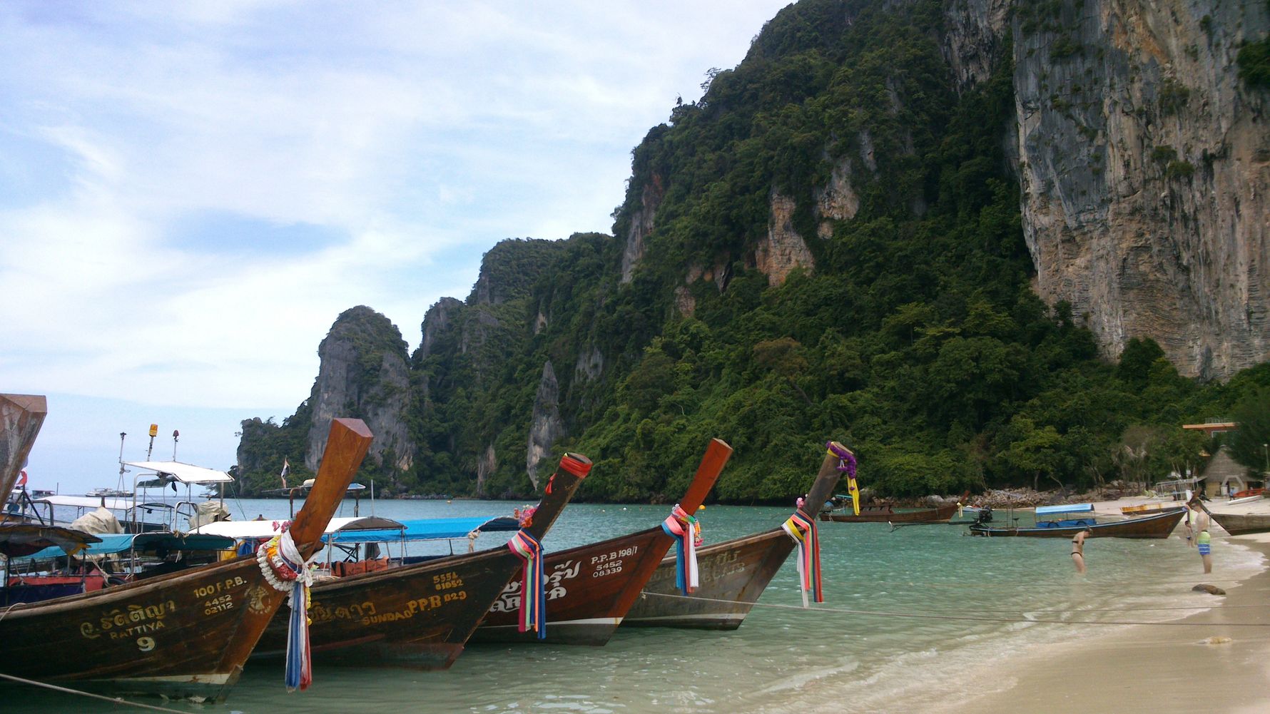Volunteer Asien: bunt geschmueckte Boote an einem Strand in Thailand