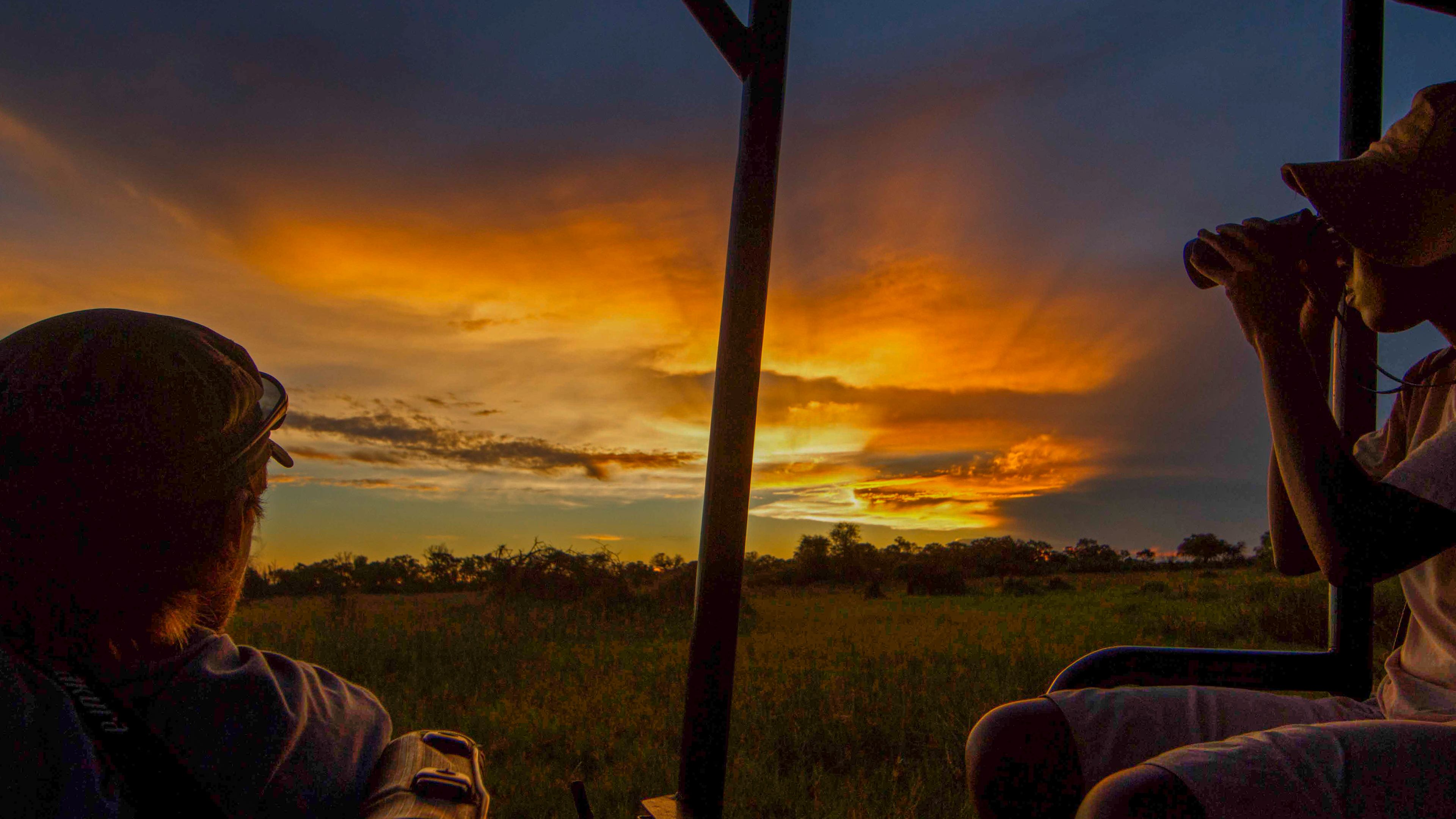 Die Studenten blicken waehrend eines Ausflugs des Rangerkurses in den botswanischen Busch auf den Sonnenuntergang