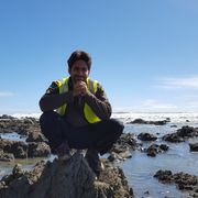 Ein freiwilliger Helfer sitzt auf einem Stein an der Kueste Neuseelands