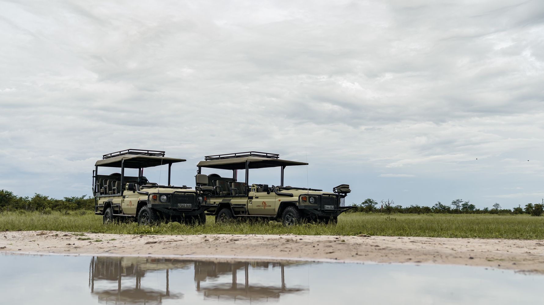 Zwei Autos an Wasserloch in Botswana