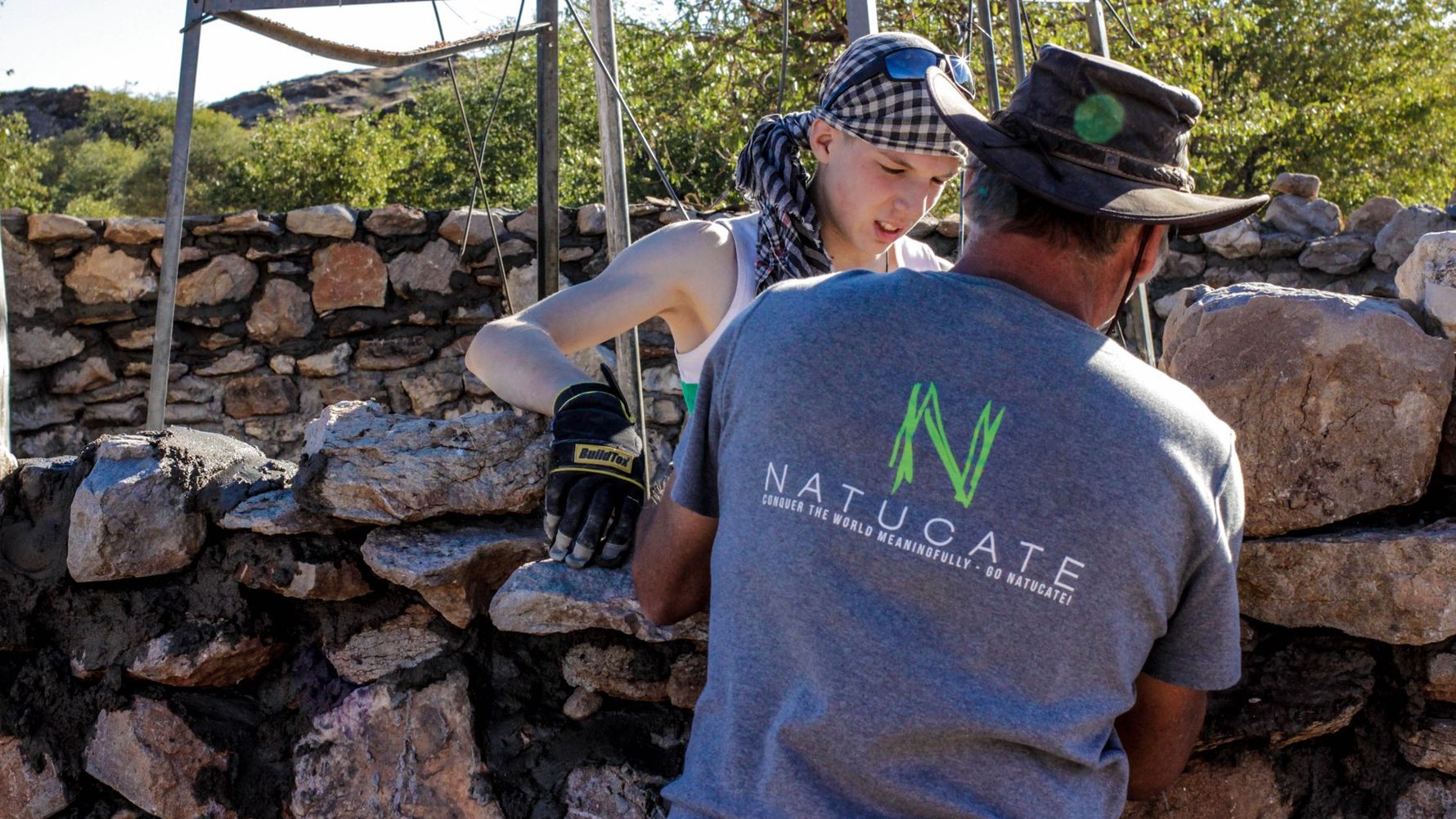 Ein Natucate-Volunteer baut mit einem anderen Volunteer eine Mauer auf