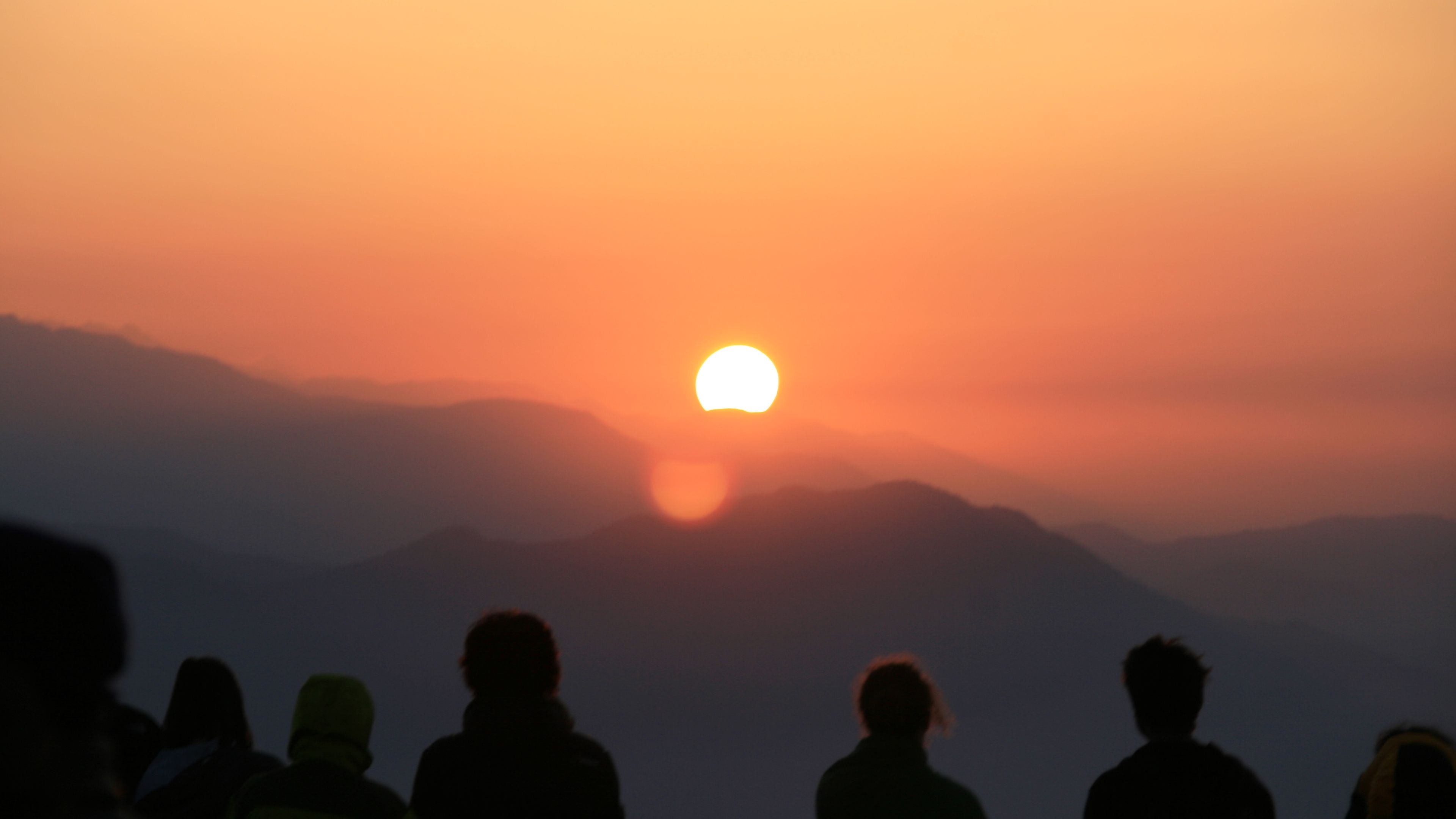 Teilnehmer des Rangerkurses in Bhutan fotografieren und beobachten den Sonnenuntergang ueber dem Gebirge