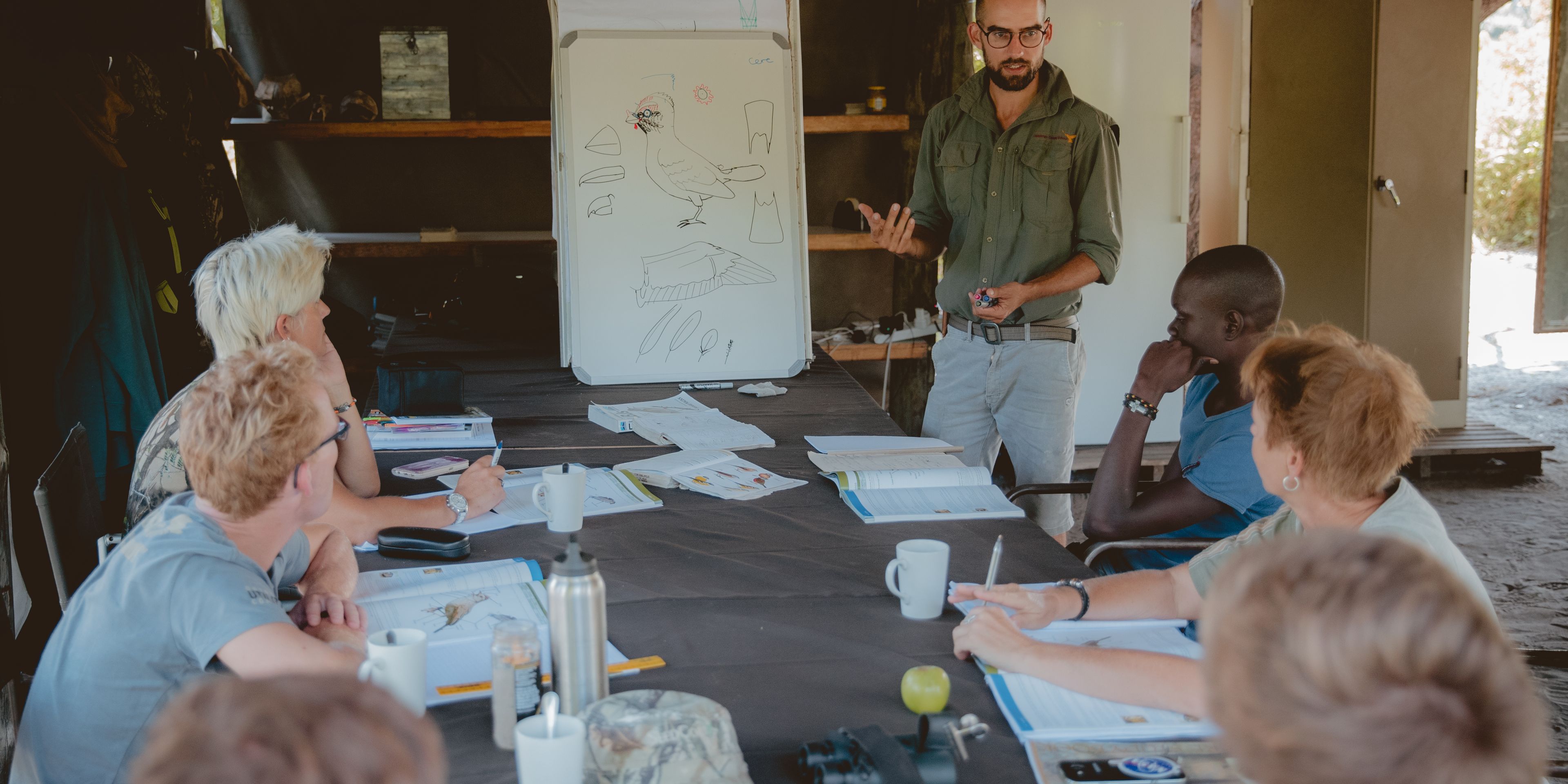 Die Studenten des Rangerkurses erhalten im Busch sitzend eine Unterrichtsstunde von ihrem Guide