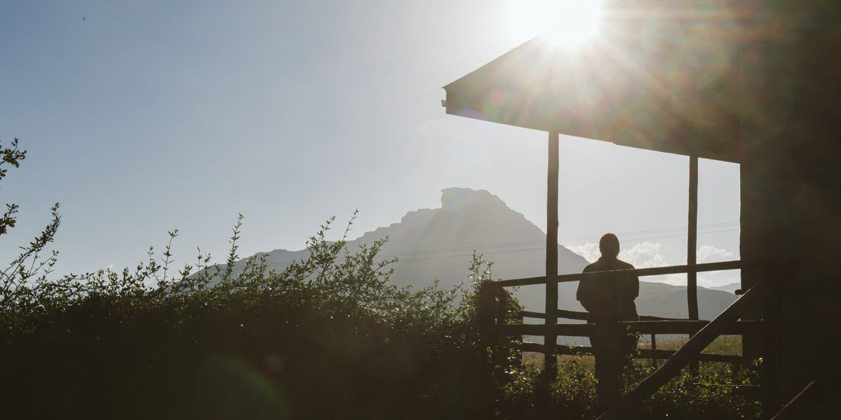 Person stands on verandah and looks at mountains