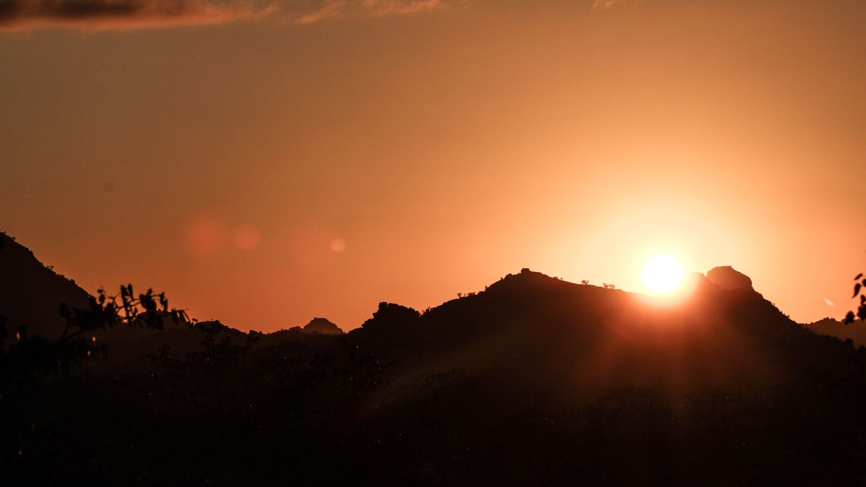 Ein Sonnenaufgang ueber eine Bergkuppe in der Wildnis Namibias