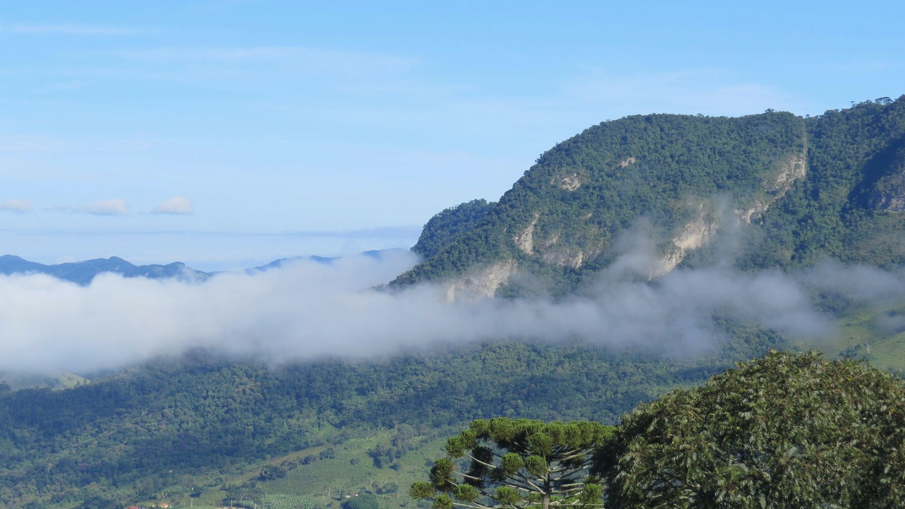 A thin strip of clouds surrounds the mountains of Sao Bento Do Sapucai