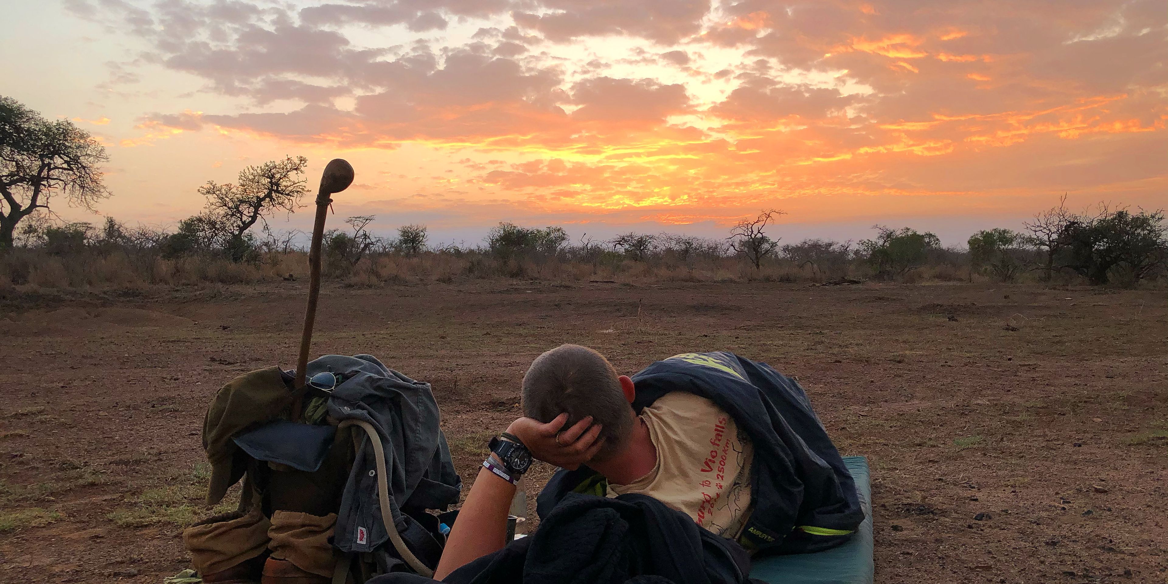 Wilderness sleep-out in Africa: Student of the African Bush Experience course in South Africa on a sleeping mat enjoying the sunset