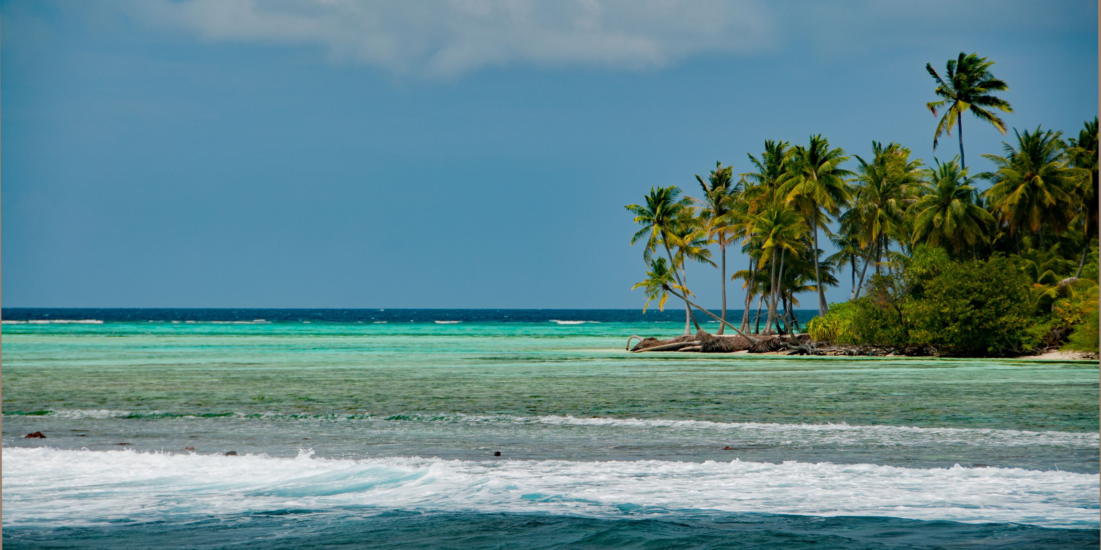 Blick auf eine Insel der Malediven, die umgeben vom tuerkisblauen Wasser des Indischen Ozean ist