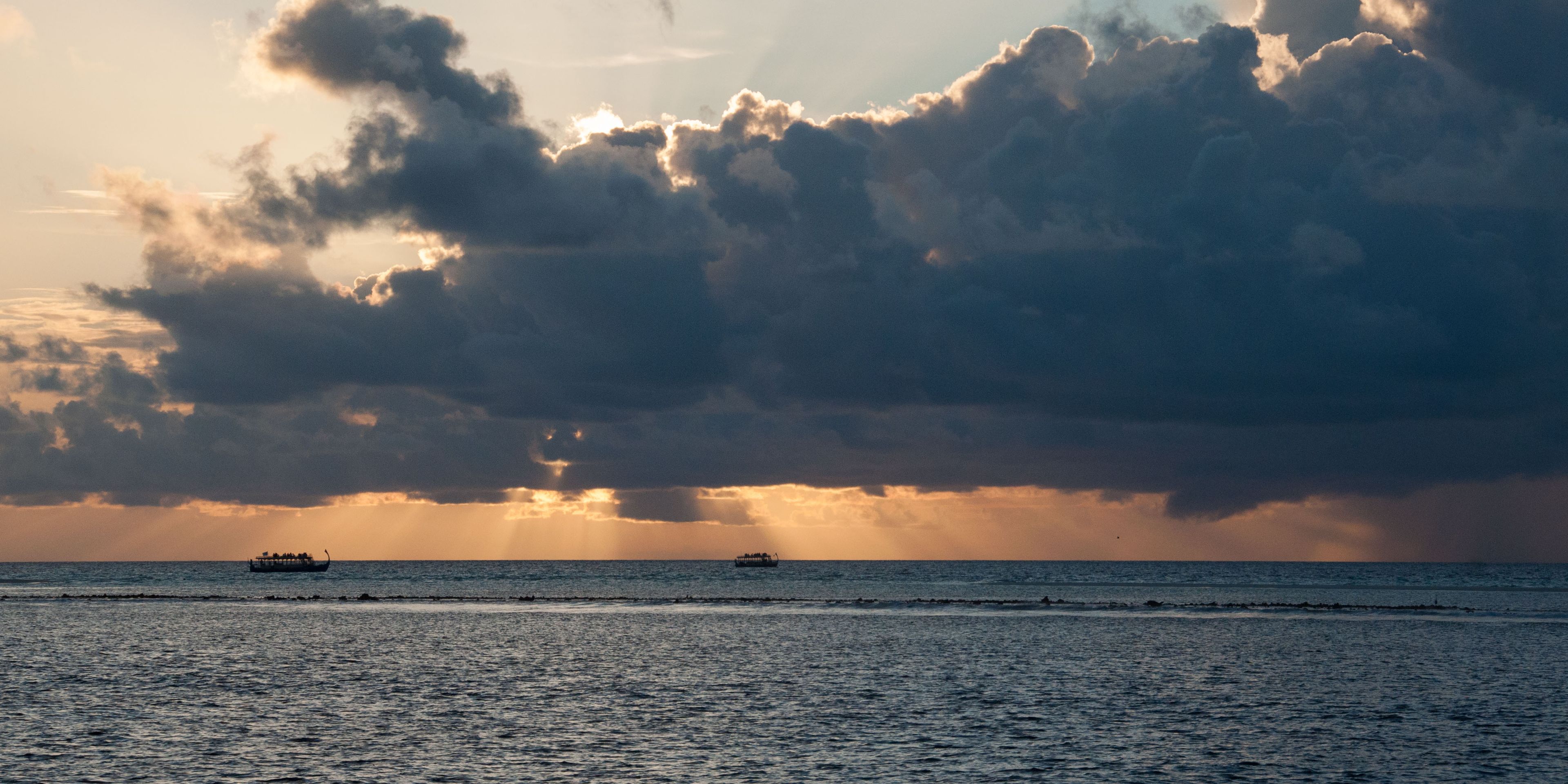 Die Abendsonne auf den Malediven scheint in sanften Pastelltoenen durch eine eindrucksvolle Wolkenformation hindurch
