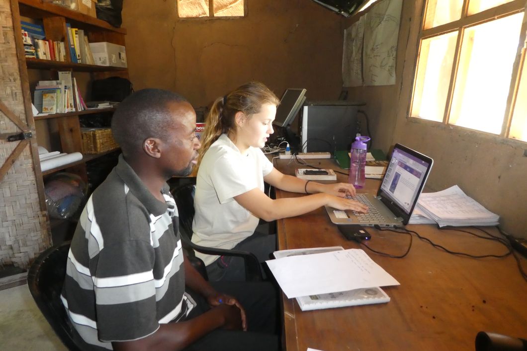 Eine Freiwillige und ein Teamleiter des Elefantenprojekts in Sambia sitzen zusammen im Camp-Buero und arbeiten