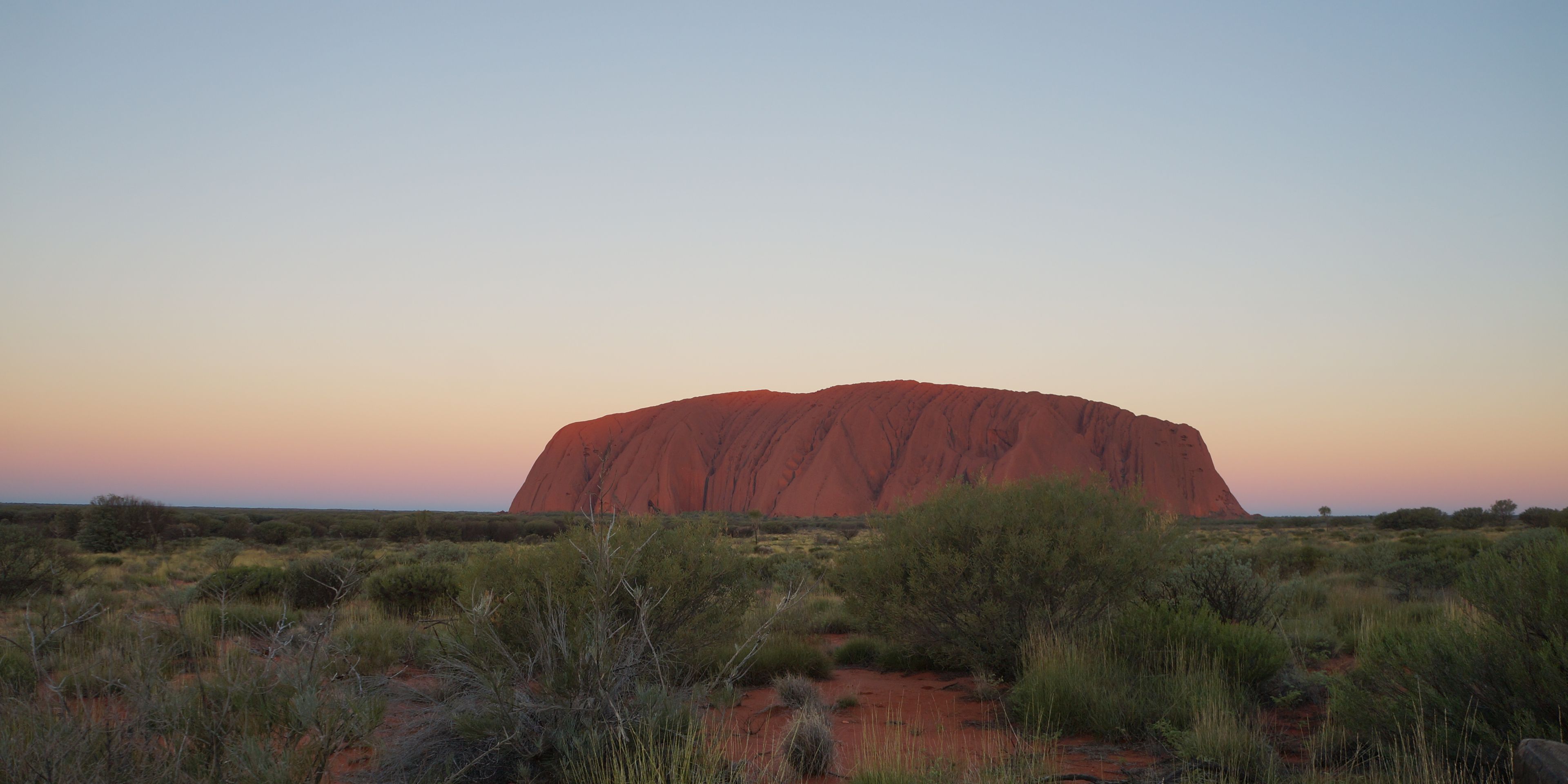 Der Ayers Rock, auch Uluru genannt, liegt majest&auml;tisch im Sonnenuntergang in Australiens Outback.
