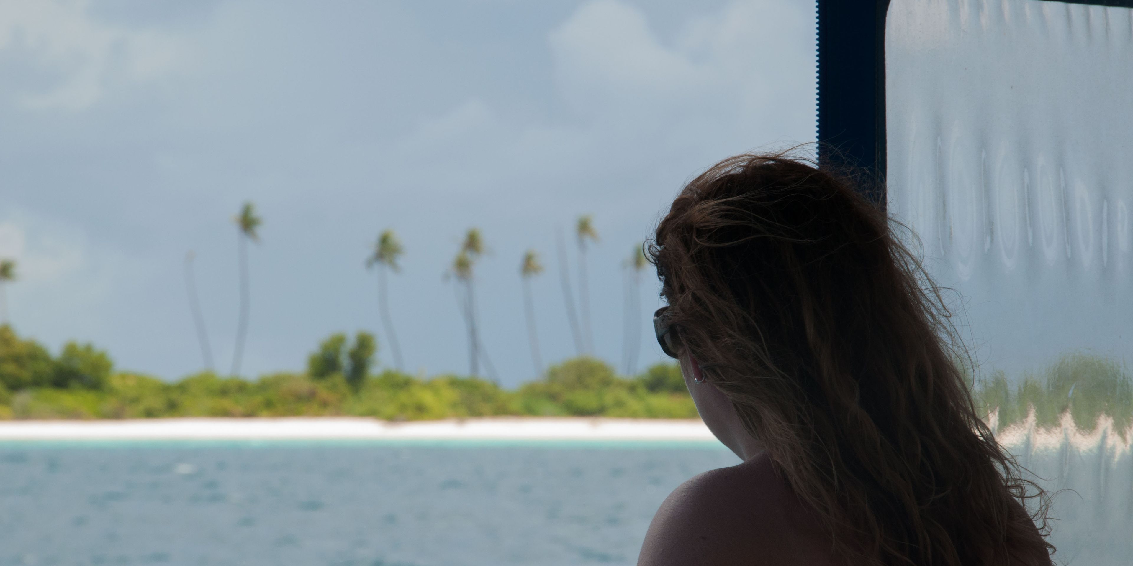 Teilnehmerin der Walhai-Expedition auf den Malediven blickt vom Forschungsboot auf eine kleine Insel im Meer