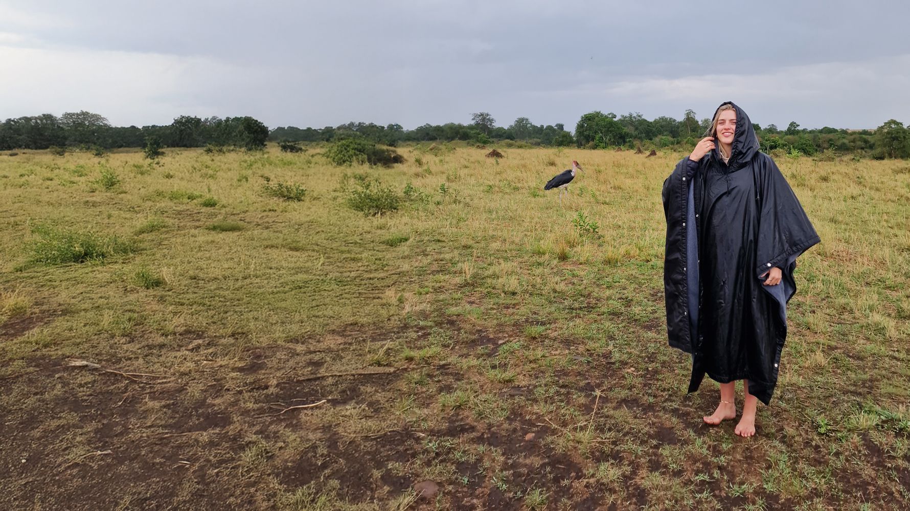 Frau mit Regenmantel steht barfu&szlig; in der Natur