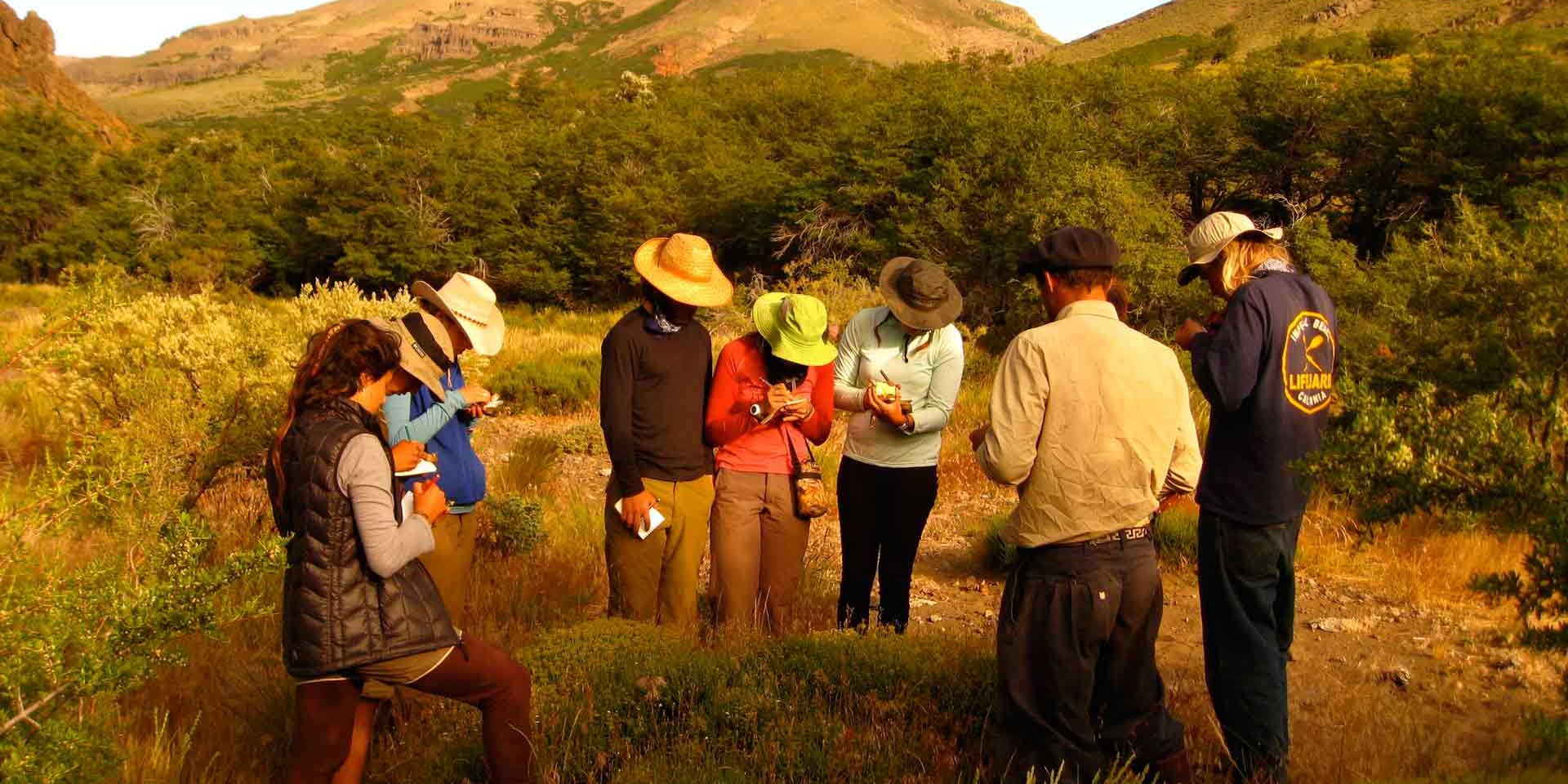 Eine Gruppe von Studenten macht sich Notizen waehrend einer Unterrichtsstunde in Patagoniens Landschaft