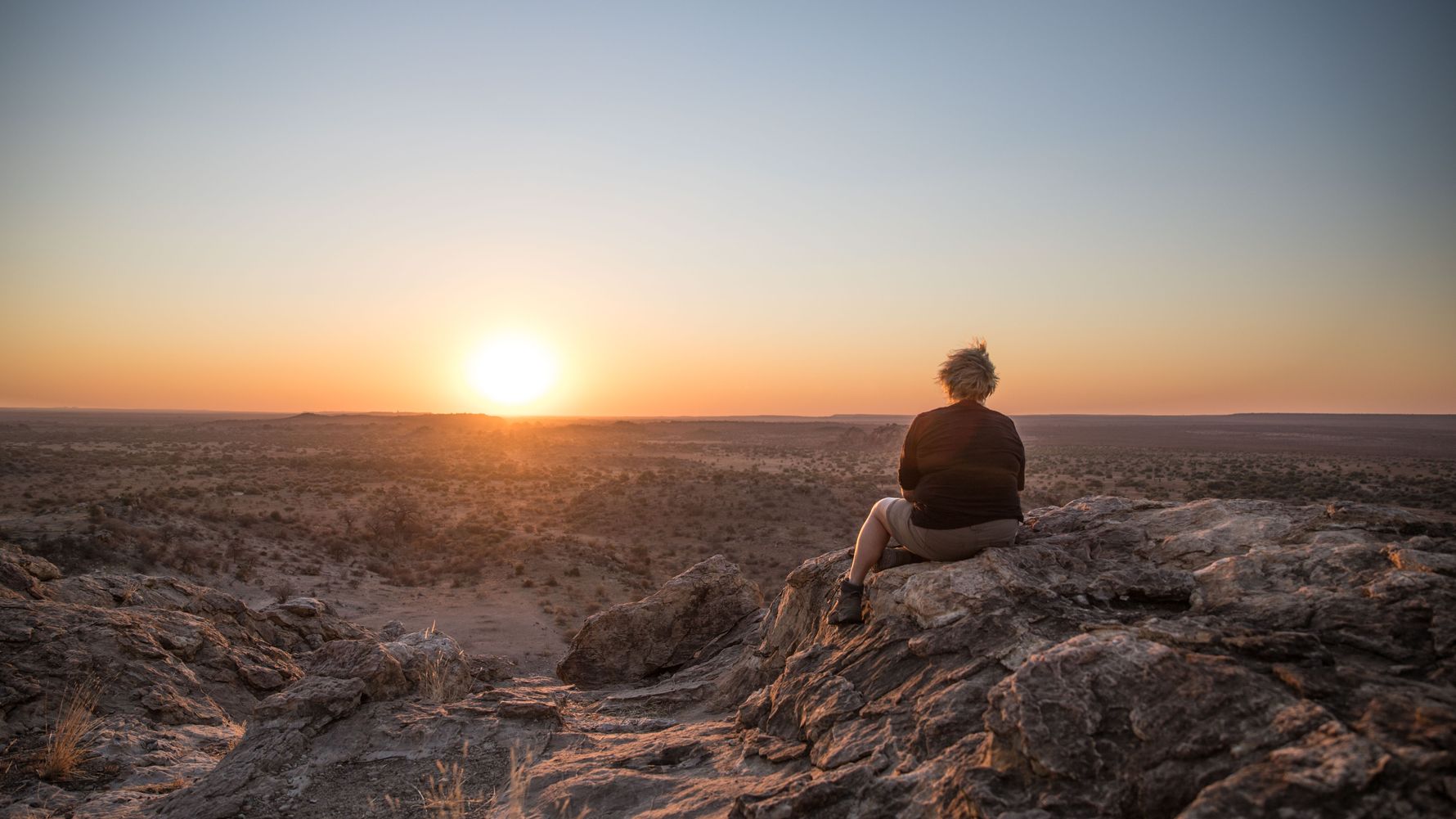 Field-Guide-Ausbildung: Eine Studentin sitzt auf einem Felsen und guckt in den Sonnenuntergang