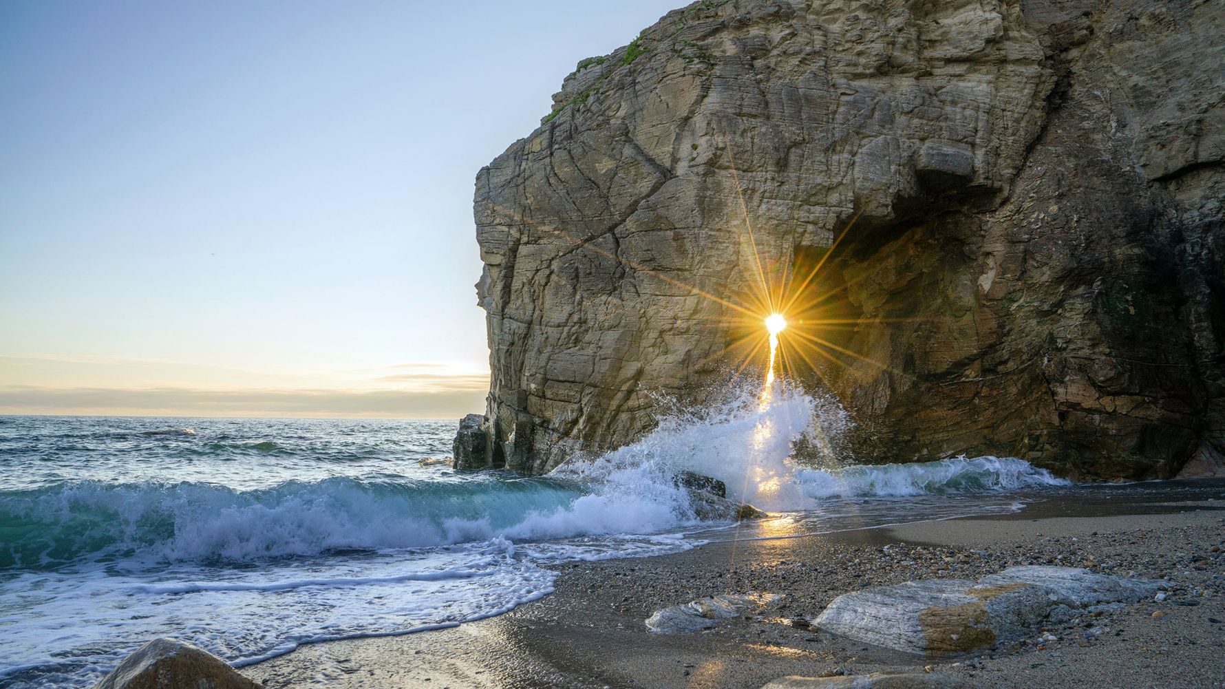 Sunbeams penetrate through a crevice on the French coast Brittany on a sandy beach