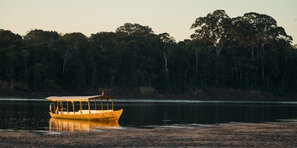 Ein Boot faehrt ueber den Amazonas und durch den Regenwald