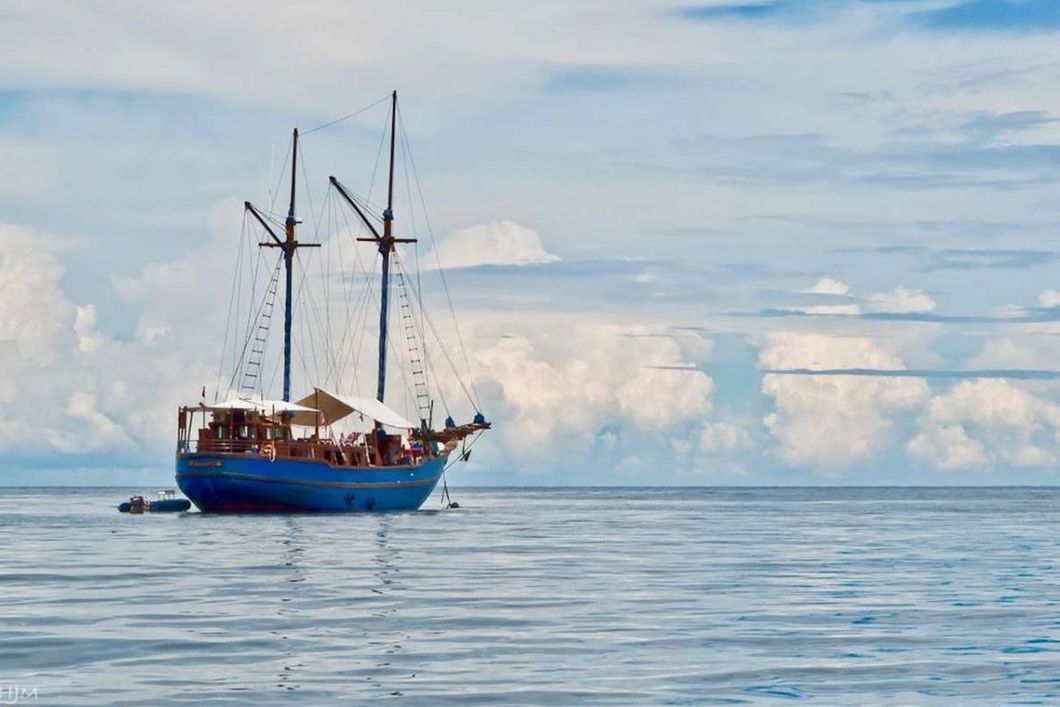 Eine Segelreise mit blauem Segelboot in tropischen Gew&auml;ssern.
