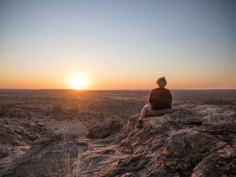 Field-Guide-Ausbildung: Eine Studentin sitzt auf einem Felsen und guckt in den Sonnenuntergang