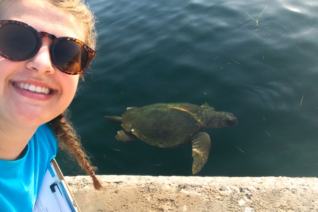 Selfie of a young woman with a turtle in the water