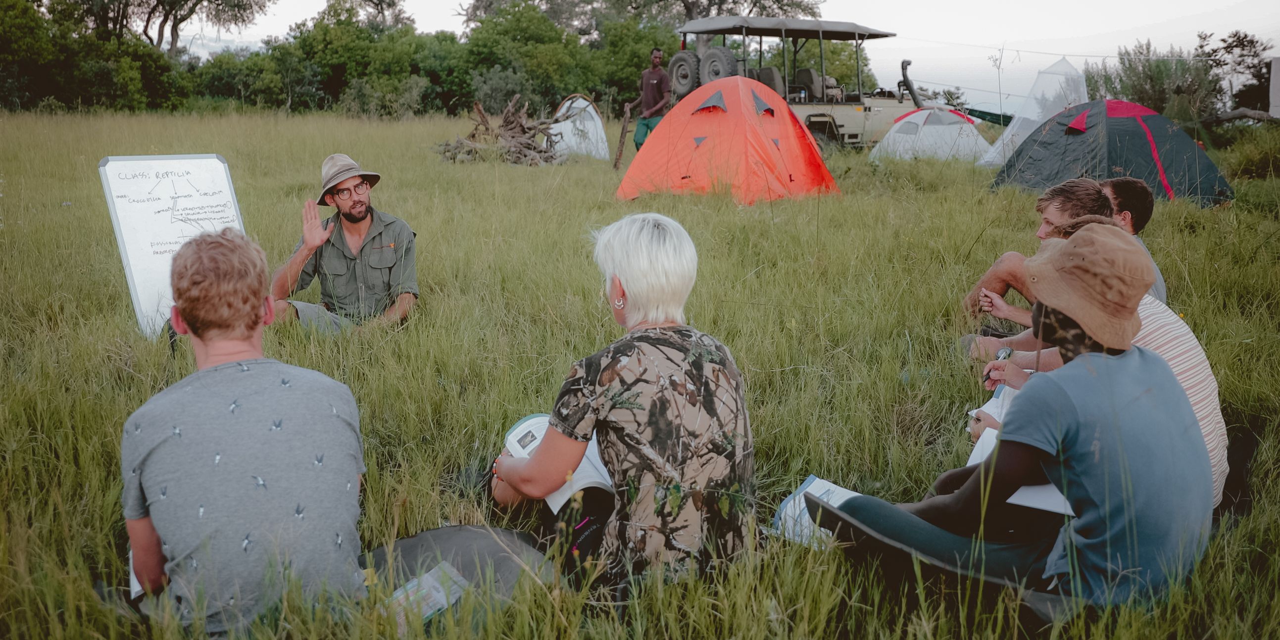 Eine Studentin sitzt vor dem Eingang ihrer Huette und erholt sich von einer Pirschwanderung