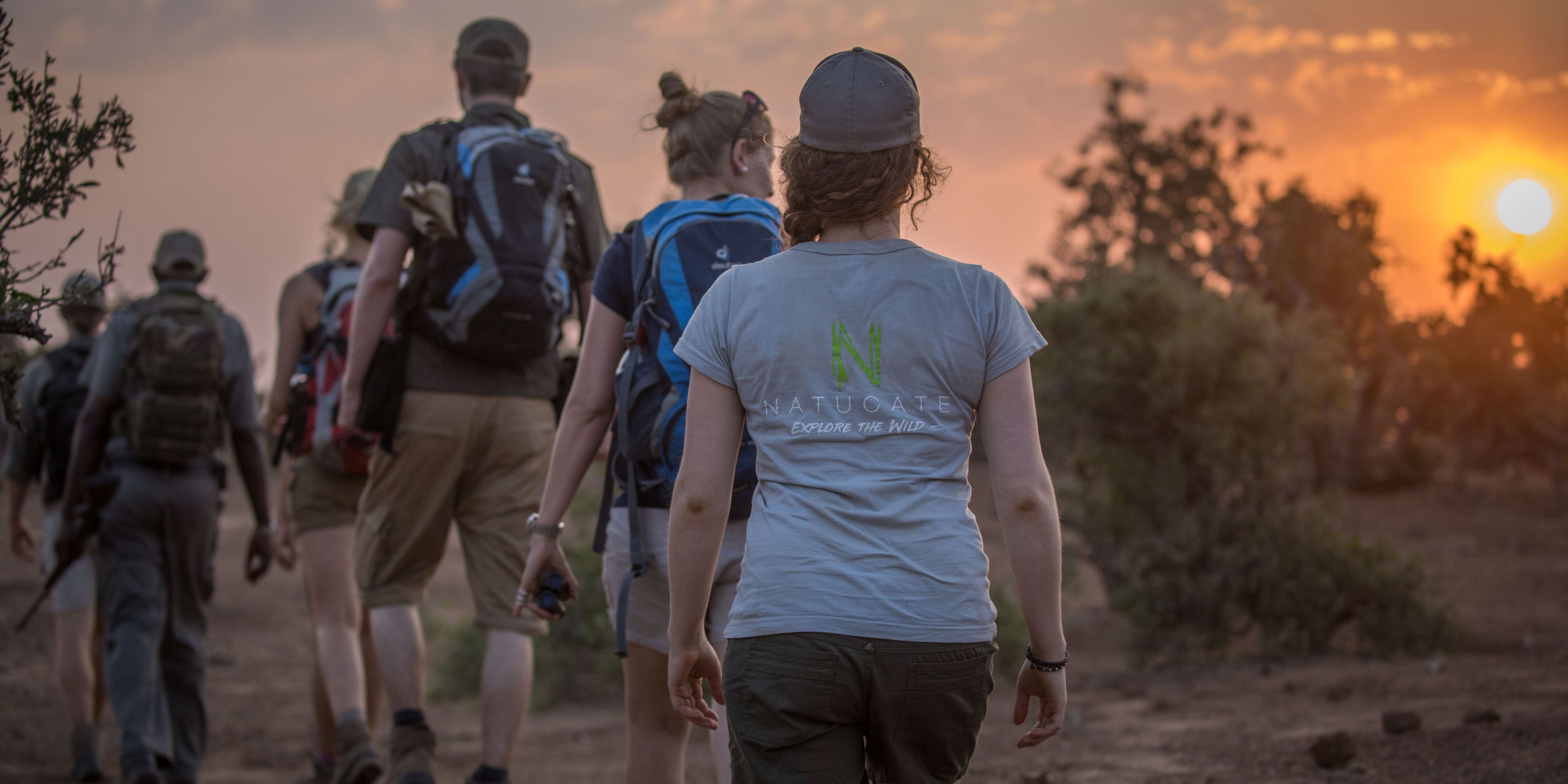 Eine Reihe von Teilnehmern wandert bei Sonnenaufgang per Pirschwanderung durch die Steppe