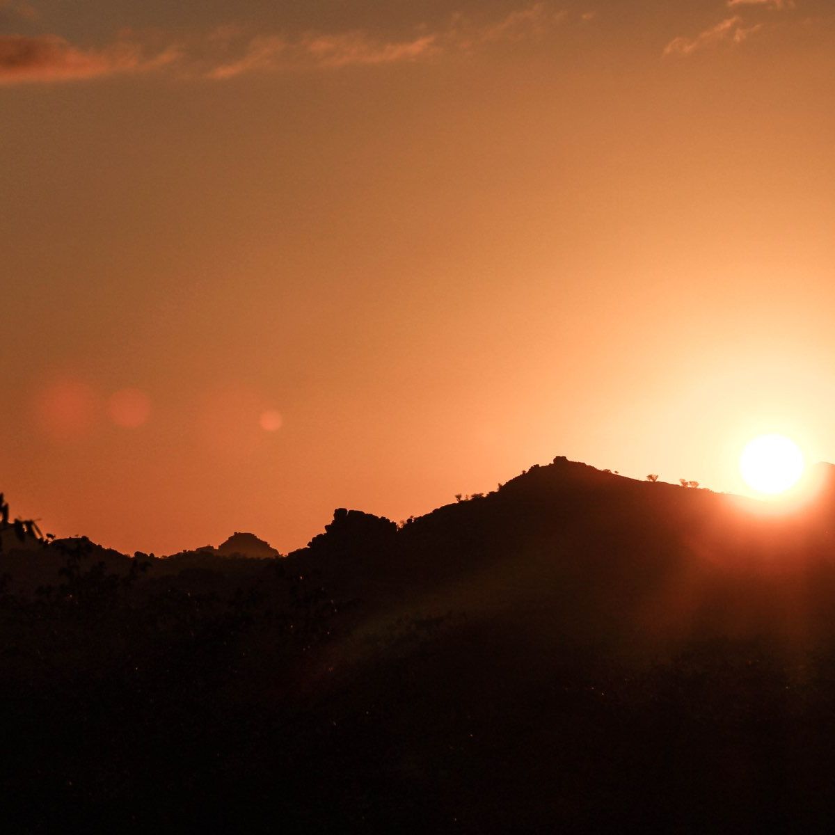 Ein Sonnenaufgang ueber eine Bergkuppe in der Wildnis Namibias