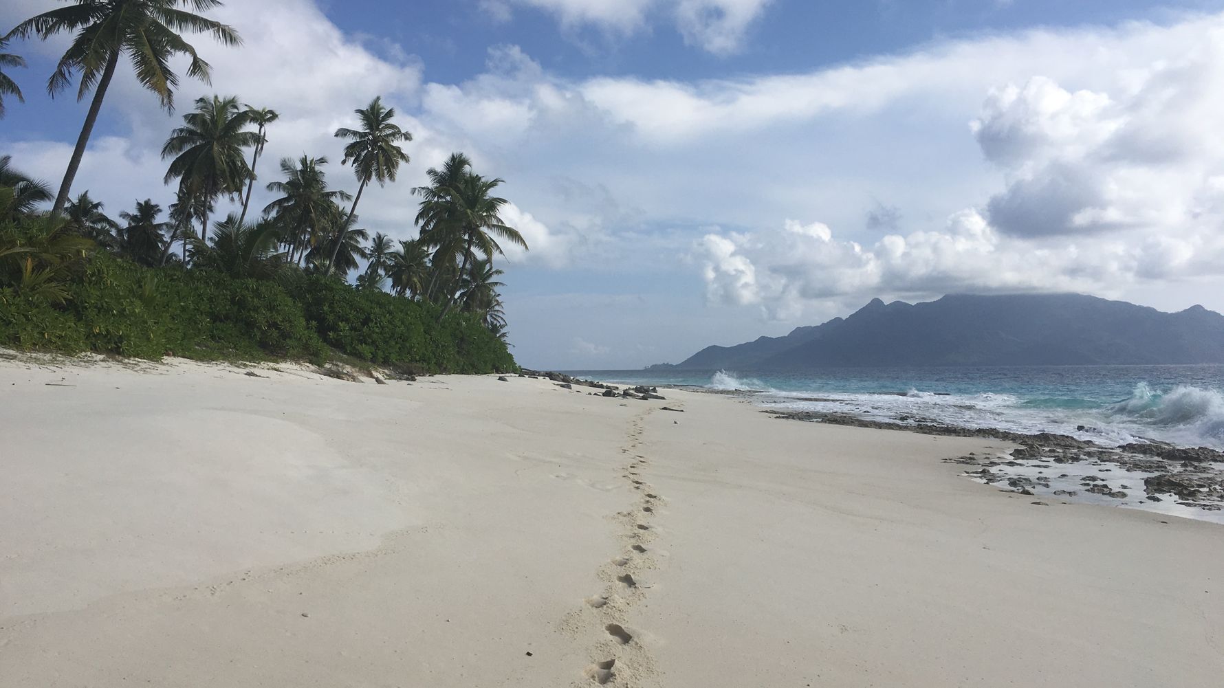 Ein Strand auf den Seychellen mit einer Nachbarinsel am Horizont