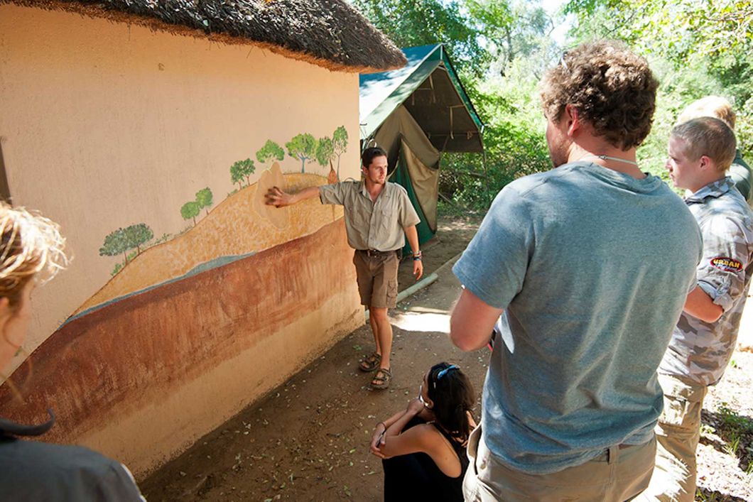 Ein Guide unterrichtet eine Gruppe von Teilnehmern anhand einer Wandzeichnung