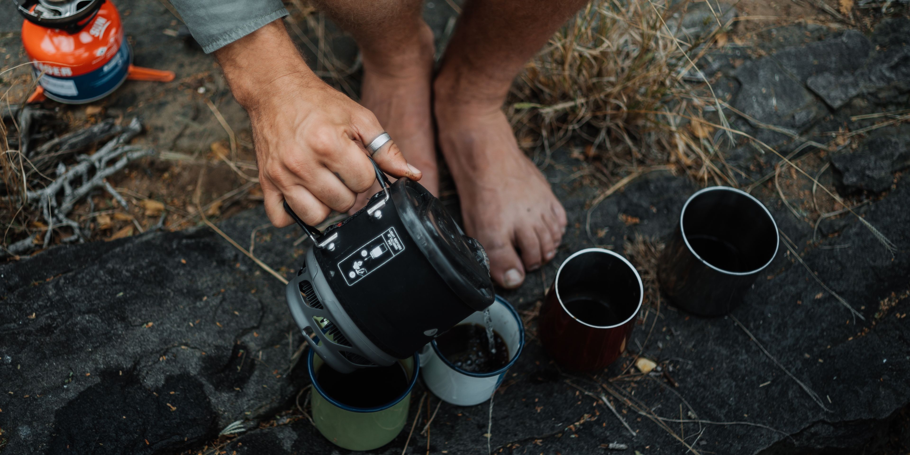 Someone purs coffe into different mugs outdoors