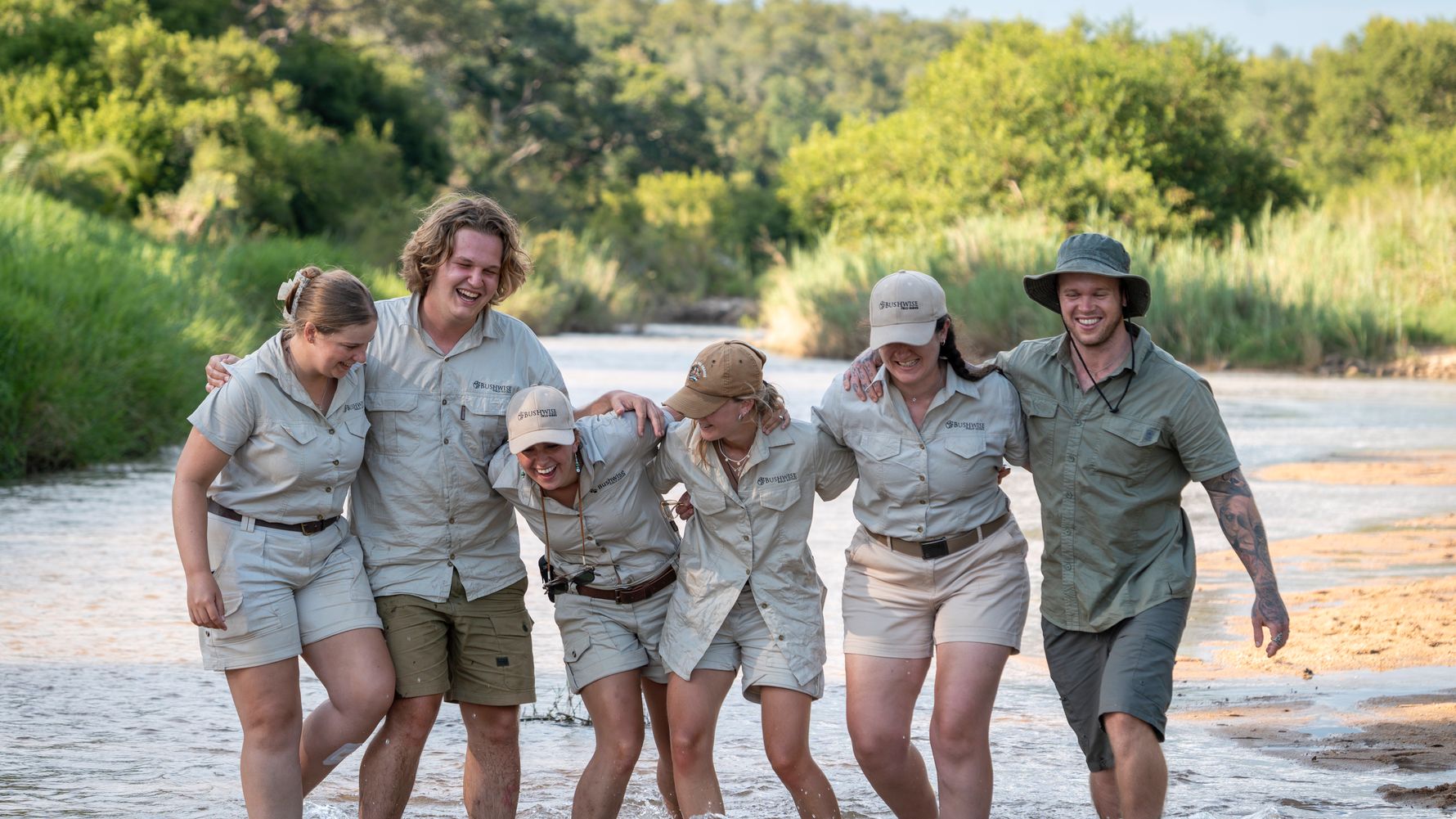 Gruppe steht lachend im Fluss