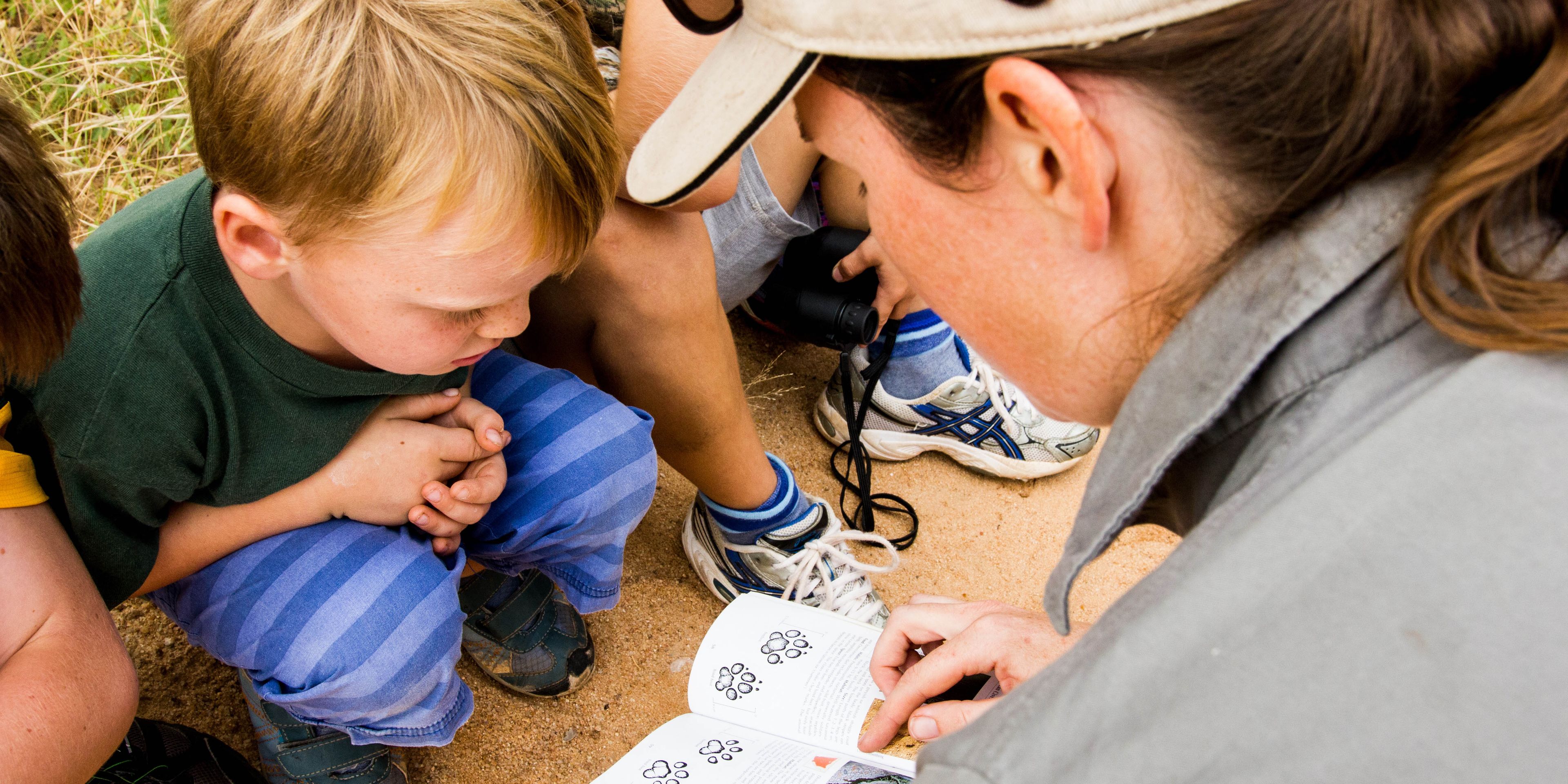 Ein Guide zeigt einer Familie auf einer Pirschwanderung in Suedafrika Insekten am Boden