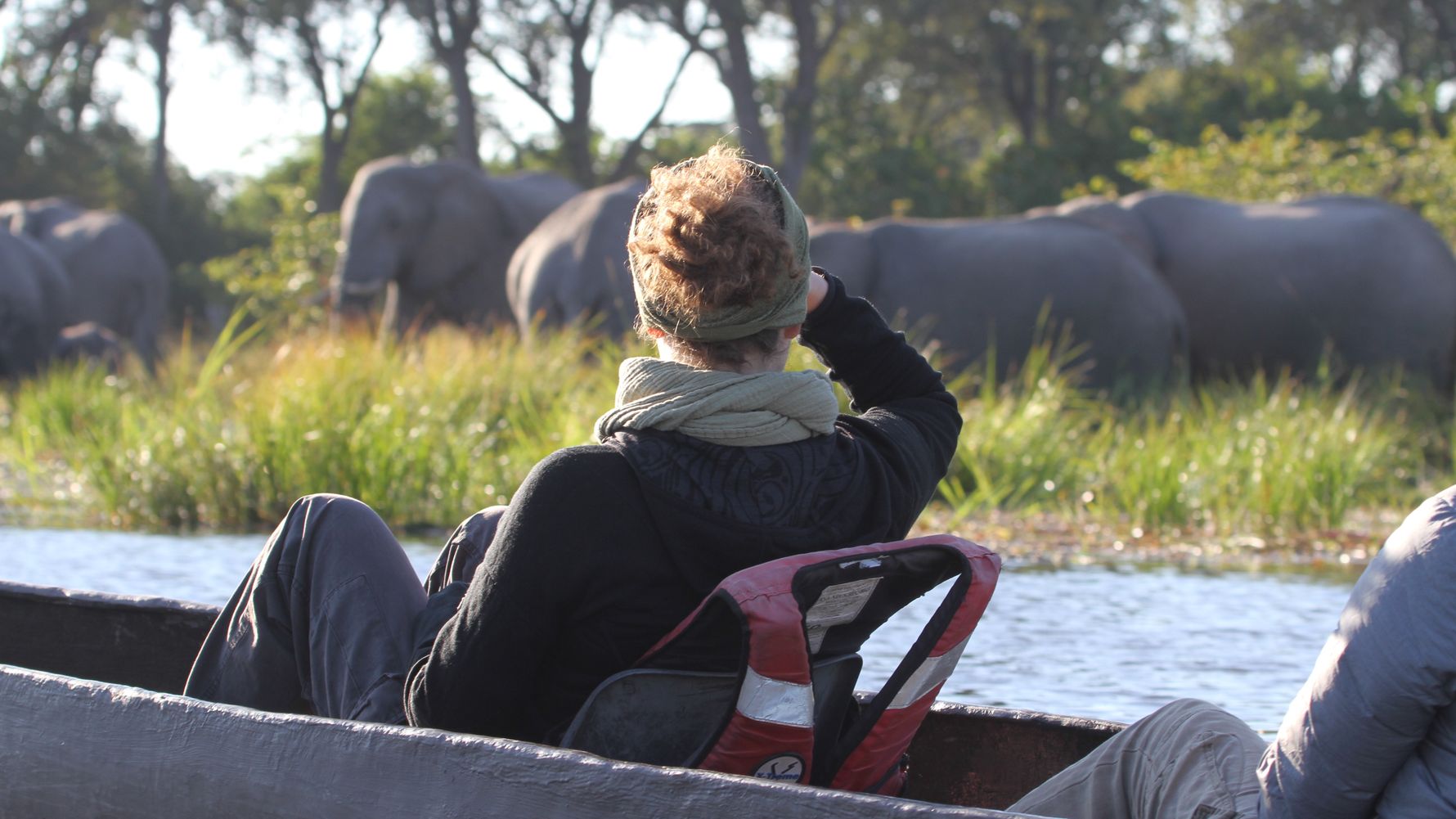 Mokorotour in Afrika: Safari-Gast im Okavango Delta beobachtet Elefanten vom Mokoro aus