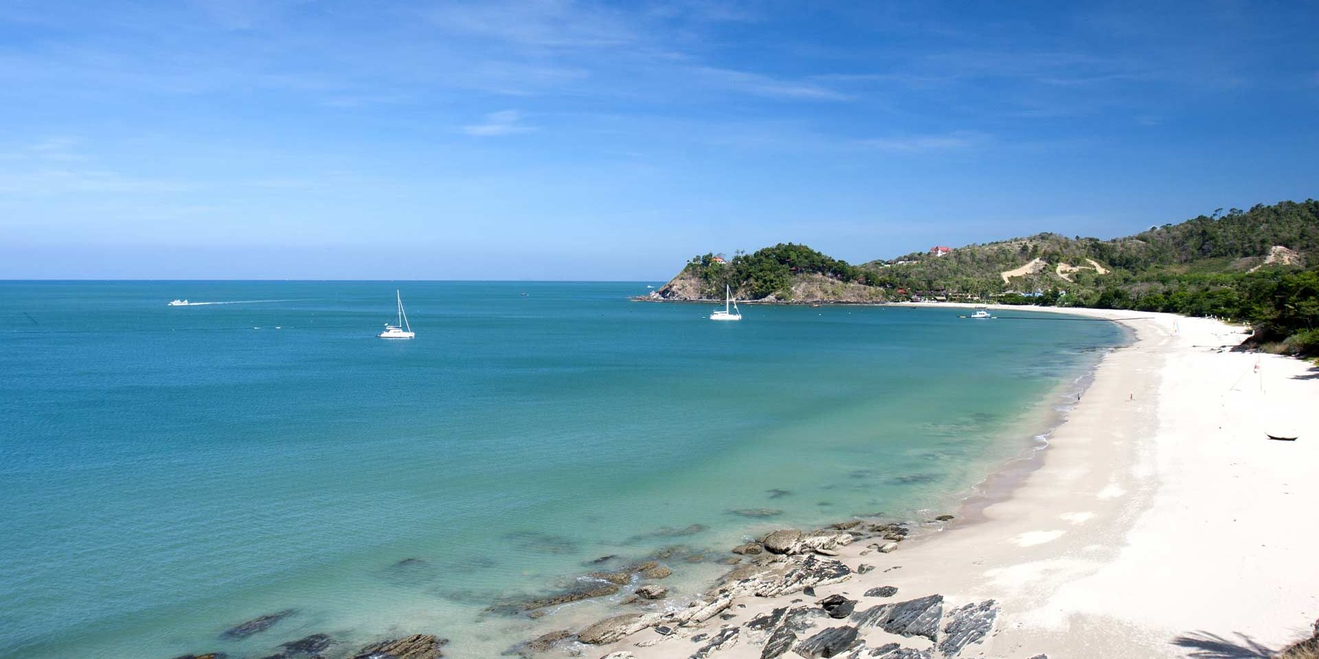 Blick auf eine Meeresbucht in Thailand: Links das blaue Meer, rechts die Kueste mit Sandstrand