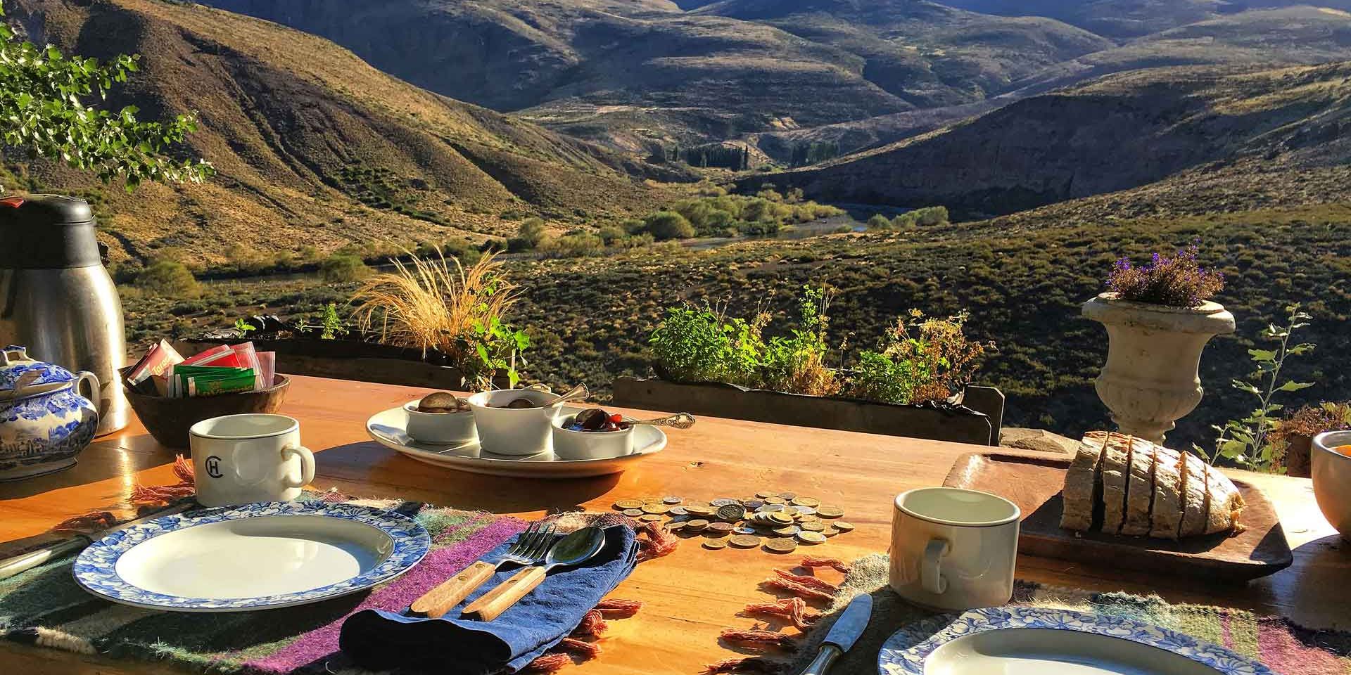 Ein gedeckter Fruehstueckstisch steht auf einer Veranda mit Blick auf die Anden