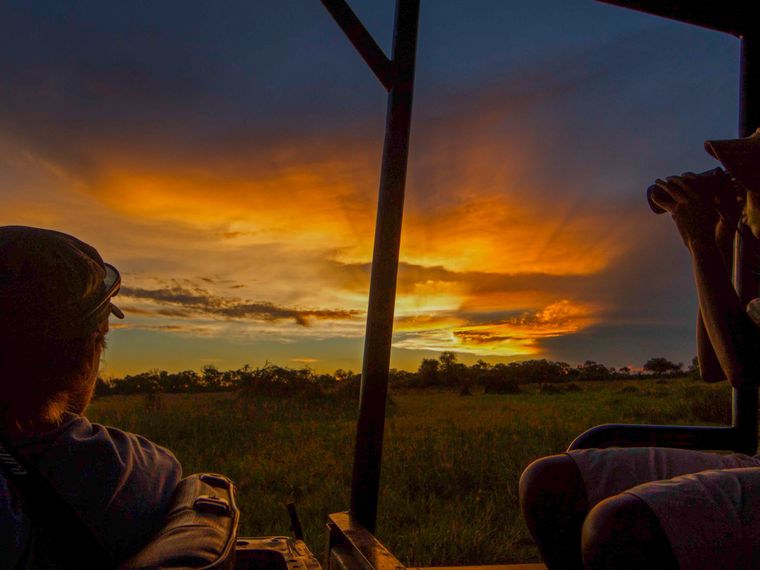 Die Studenten blicken waehrend eines Ausflugs des Rangerkurses in den botswanischen Busch auf den Sonnenuntergang