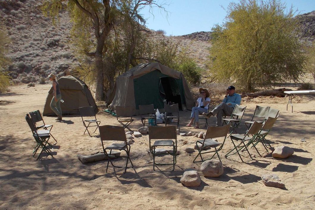 Freiwillige sitzen auf Stuehlen im mobilen Volunteercamp unseres Elefantenschutzprojekts in Namibia.