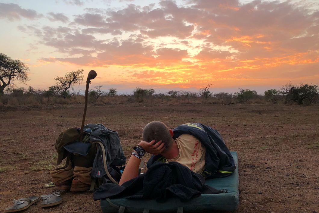 Wilderness sleep-out in Africa: Student of the African Bush Experience course in South Africa on a sleeping mat enjoying the sunset