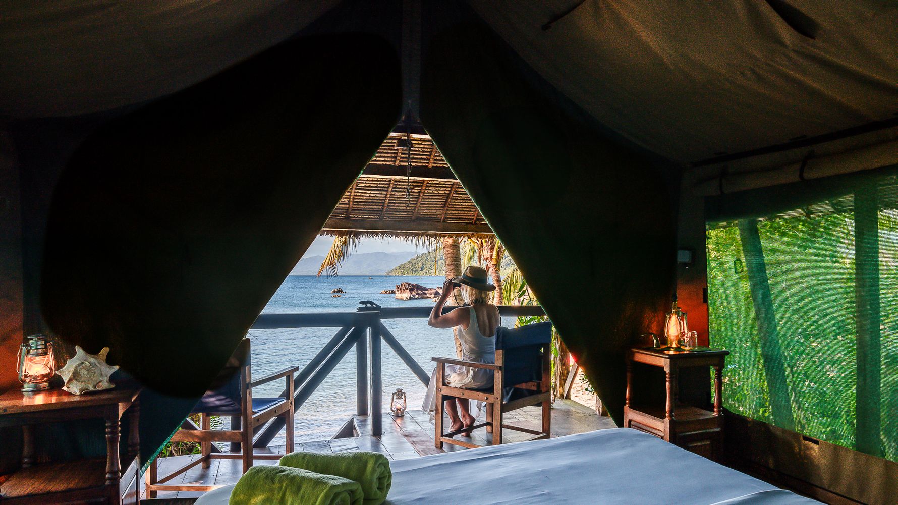 Bed and tent camp with a view of a veranda and a woman sitting