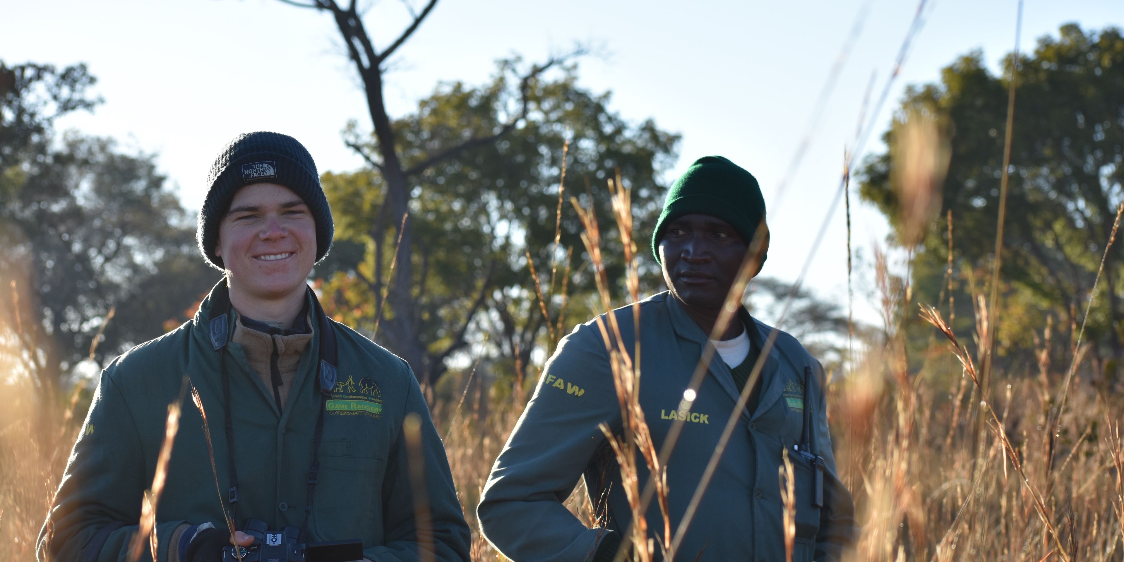 Ein Artenschutz-Volunteer und ein Teamleiter des Elefantenprojekts in Sambia stehen zusammen im Feld
