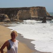 Auslandsaufenthalt in Kalifornien: Eine Freiwillige am Strand mit Klippen im Hintergrund