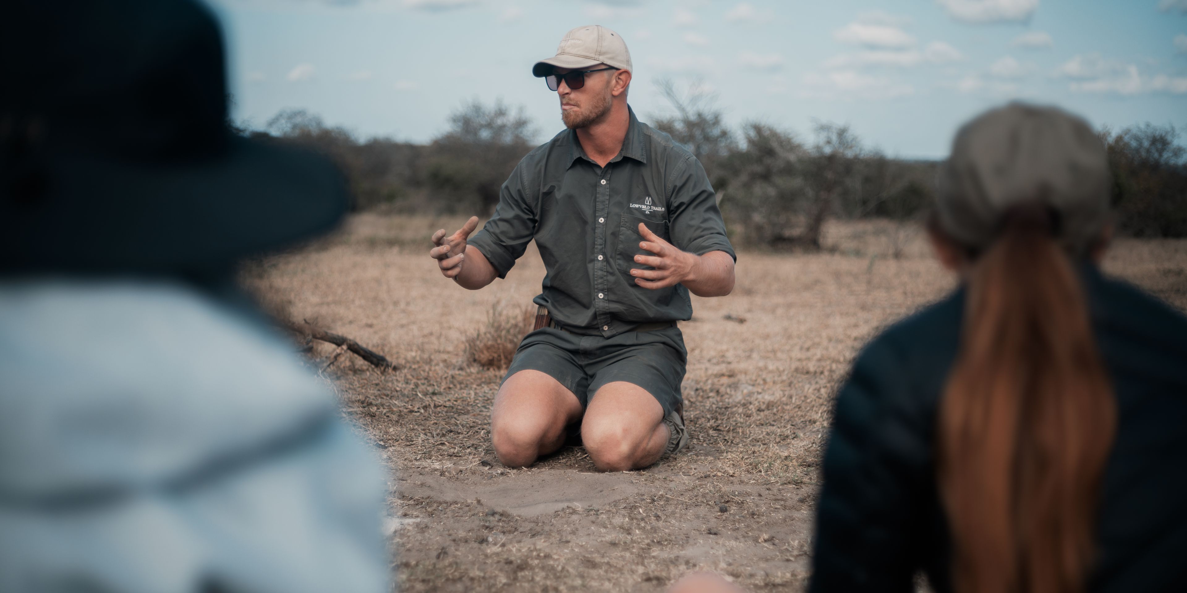 Man explains something sitting on the ground outdoors