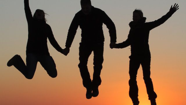 Familiensafari Afrika: Silhouette von Safari-Gaesten, die bei Sonnenuntergang in die Luft springen