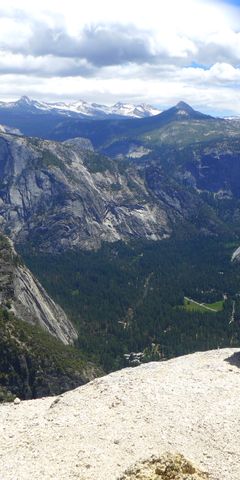 Eine Freiwillige sitzt auf einem Felsvorsprung und blickt auf die Weiten des Yosemite Nationalparks.