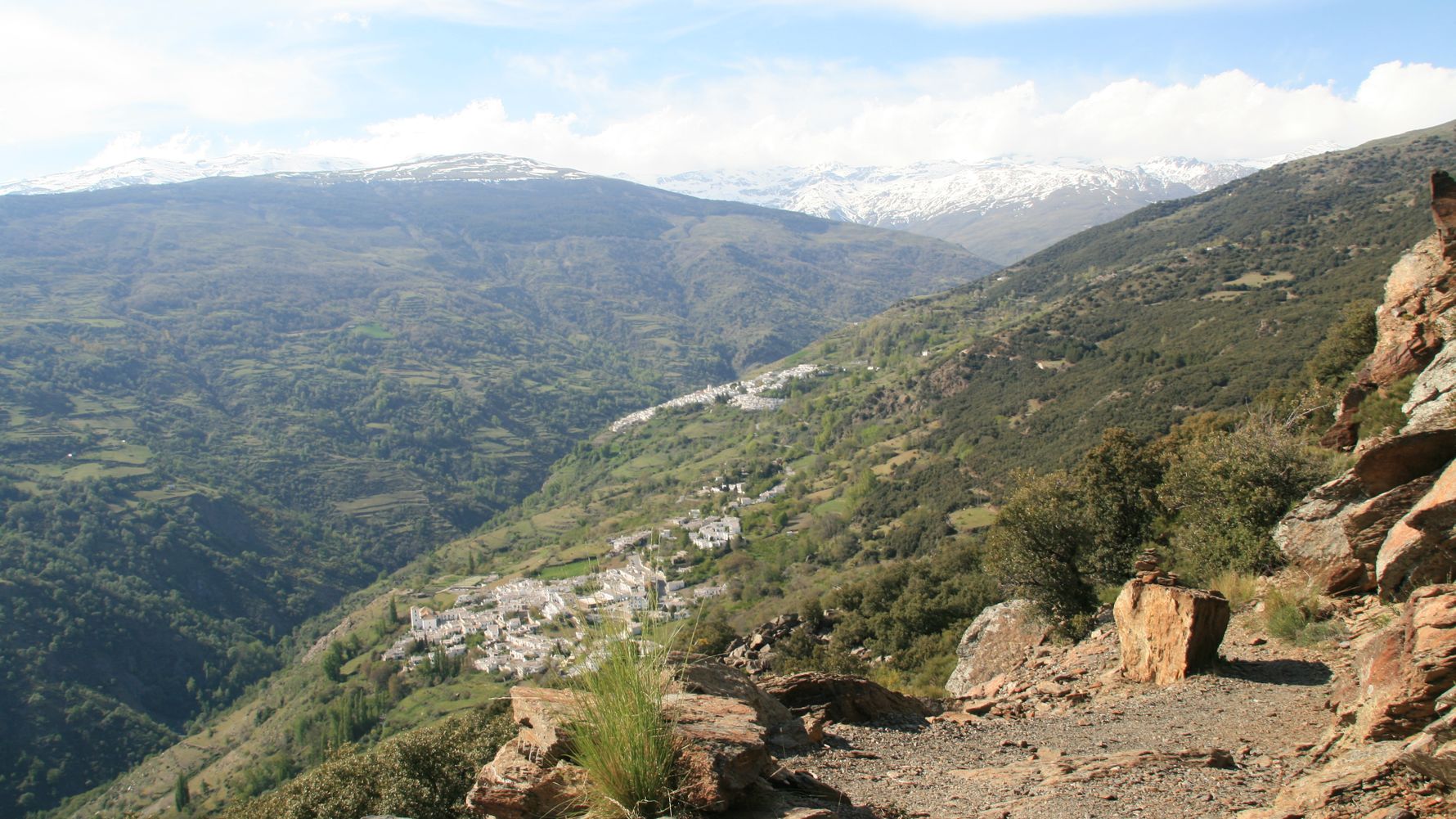 Blick von einem Aussichtspunkt ueber ein Tal mit einem kleinem Bergdorf