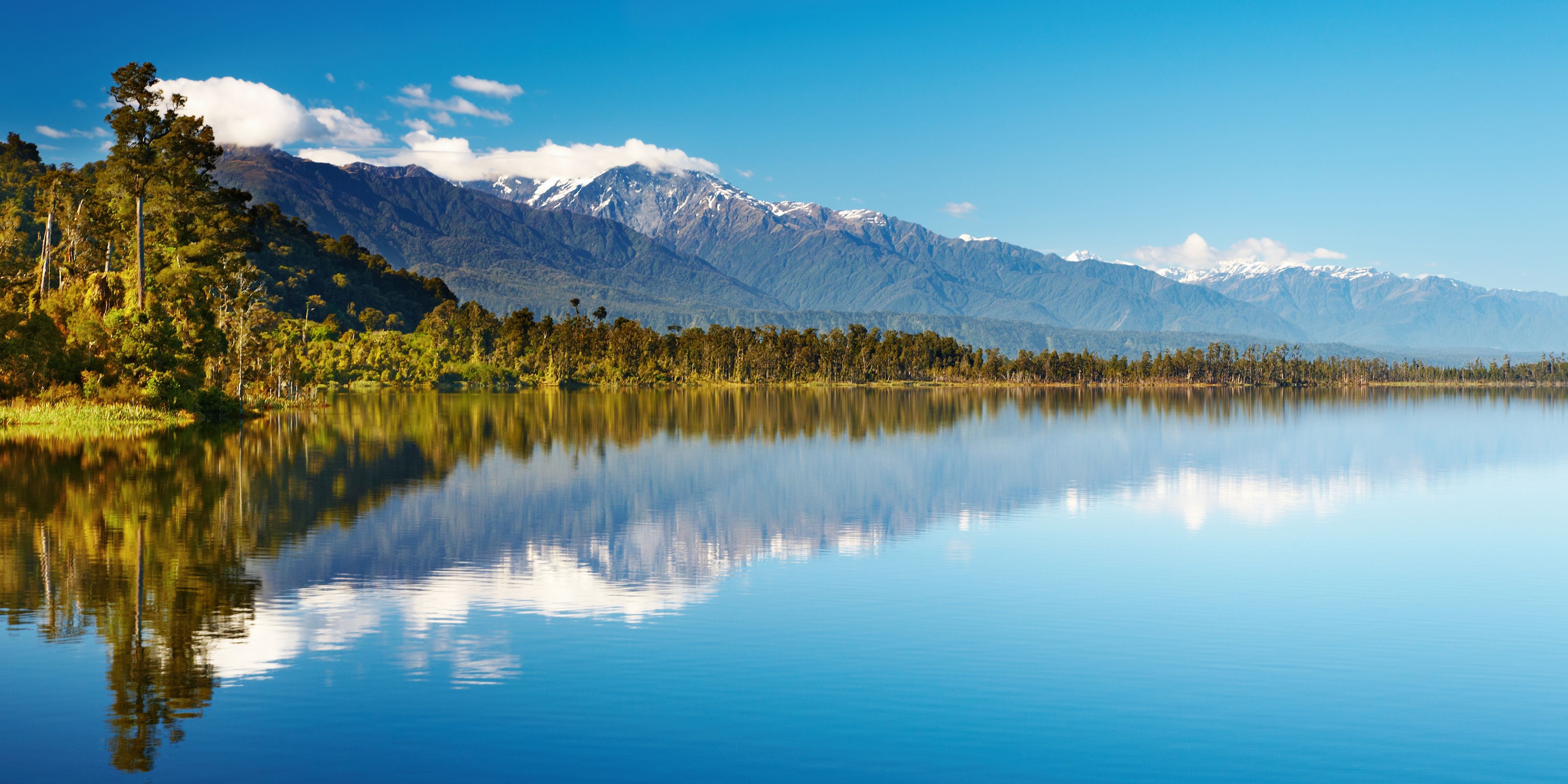 Looking over a lake in New Zealand; A forrest and an mountainrange in the backround