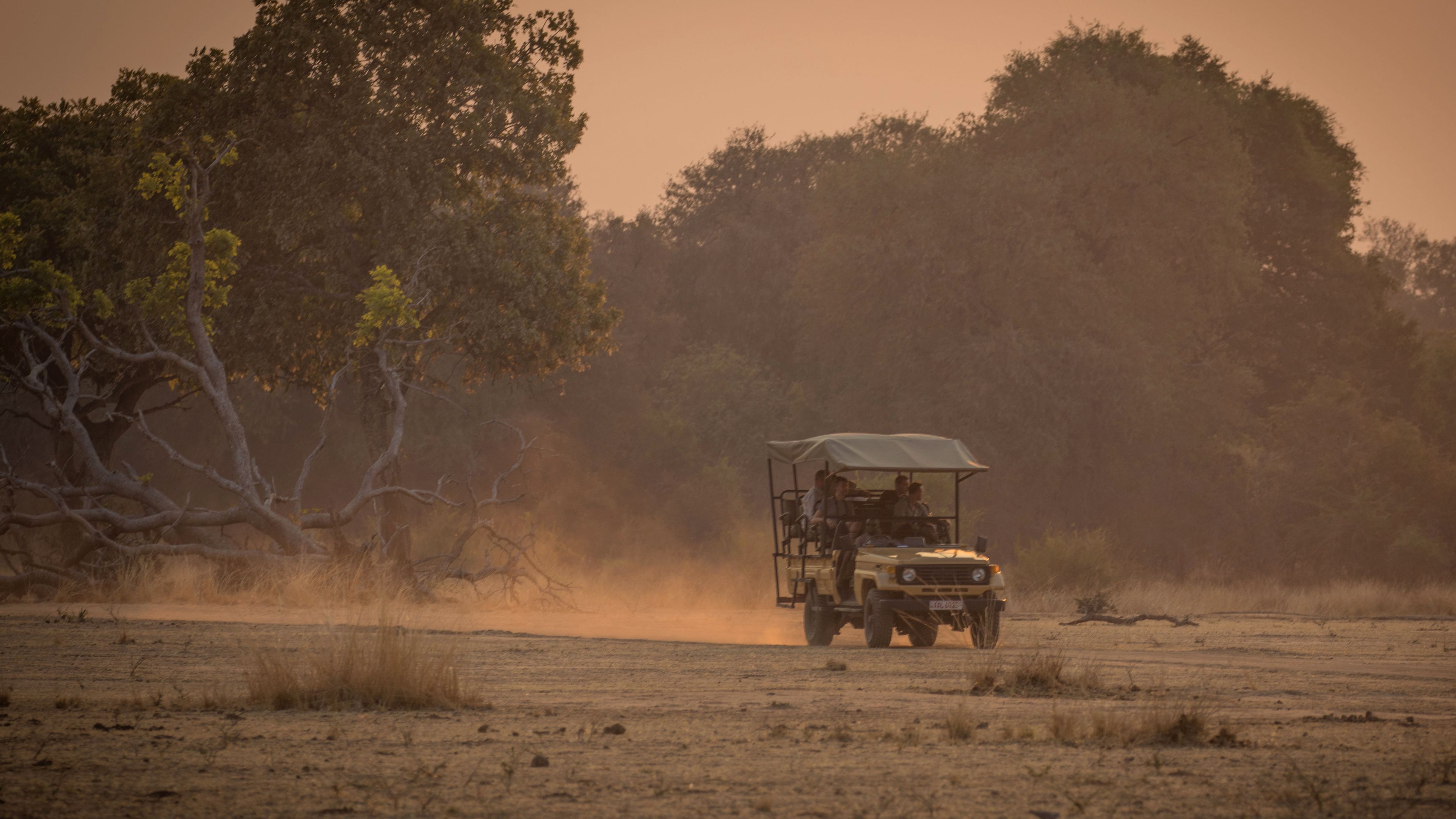 Pirschfahrt in Afrika: Game Drive-Fahrzeug in der afrikanischen Savanne bei Sonnenuntergang